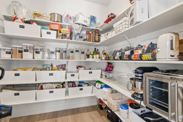 870 North Ada Loop Lehi, UT 84048 - Photo 16 of 51 Walk-in pantry featuring extensive built-in shelving, white shiplap-style walls, and wood-finish flooring