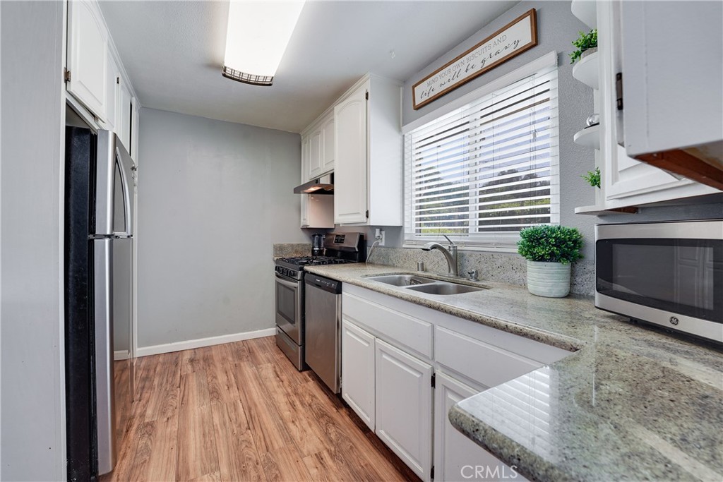 5734 Mountain View Avenue Riverside, CA 92504 - Photo 9 of 28 a kitchen with stainless steel appliances granite countertop a sink a stove and a wooden floors