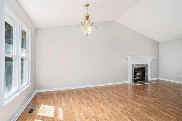 a view of empty room with wooden floor and fireplace