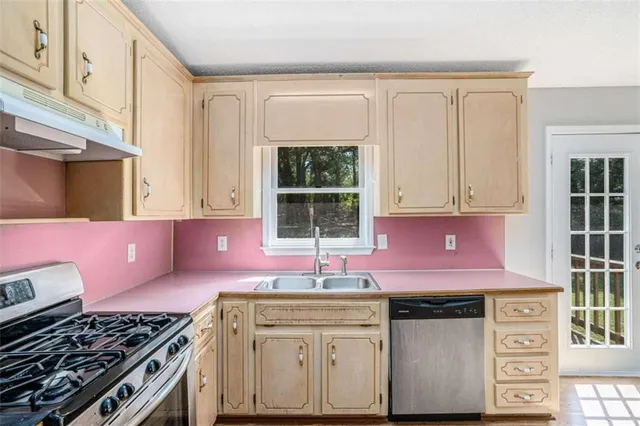 a kitchen with cabinets a window and stainless steel appliances