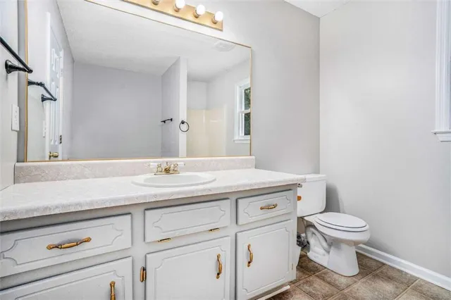a bathroom with a granite countertop toilet sink and mirror