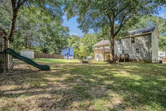 a view of an house with backyard and a tree
