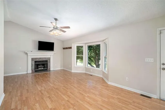 a view of a livingroom with a fireplace a ceiling fan and wooden floor