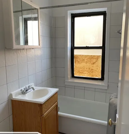 a bathroom with a sink a bathtub and next to a window