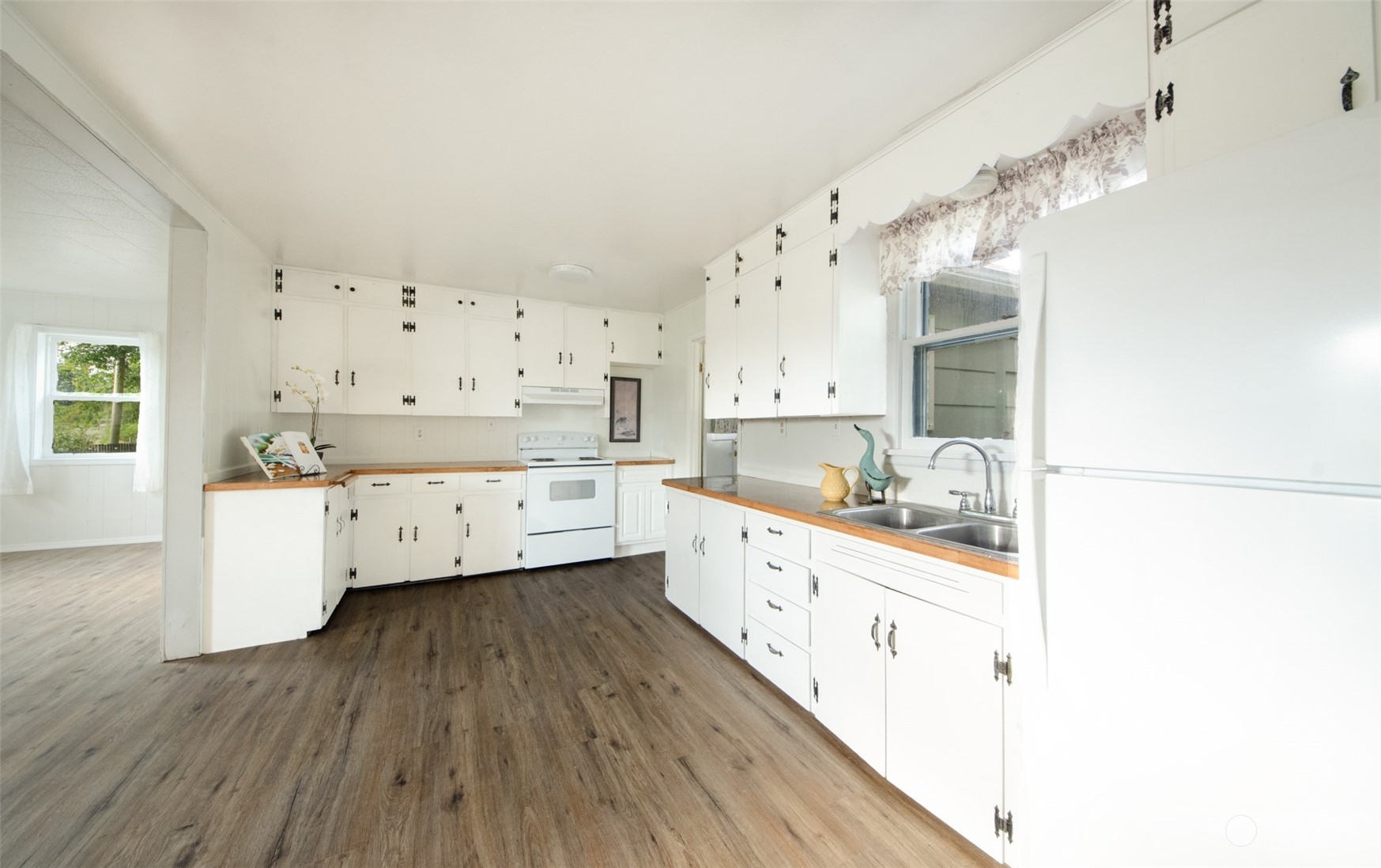18118 Bend Street Southwest Rochester, WA 98579 - Photo 4 of 13 a large white kitchen with a lot of cabinets and wooden floor