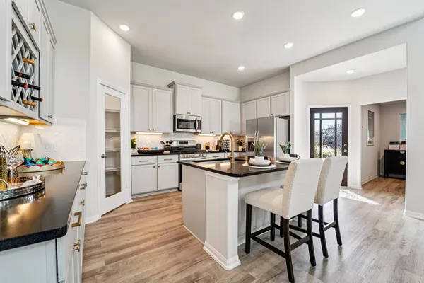 a kitchen with kitchen island a sink stainless steel appliances and white cabinets
