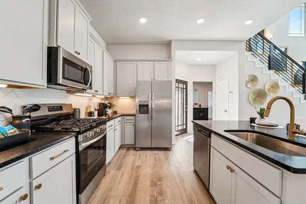 a kitchen with granite countertop a sink cabinets and stainless steel appliances