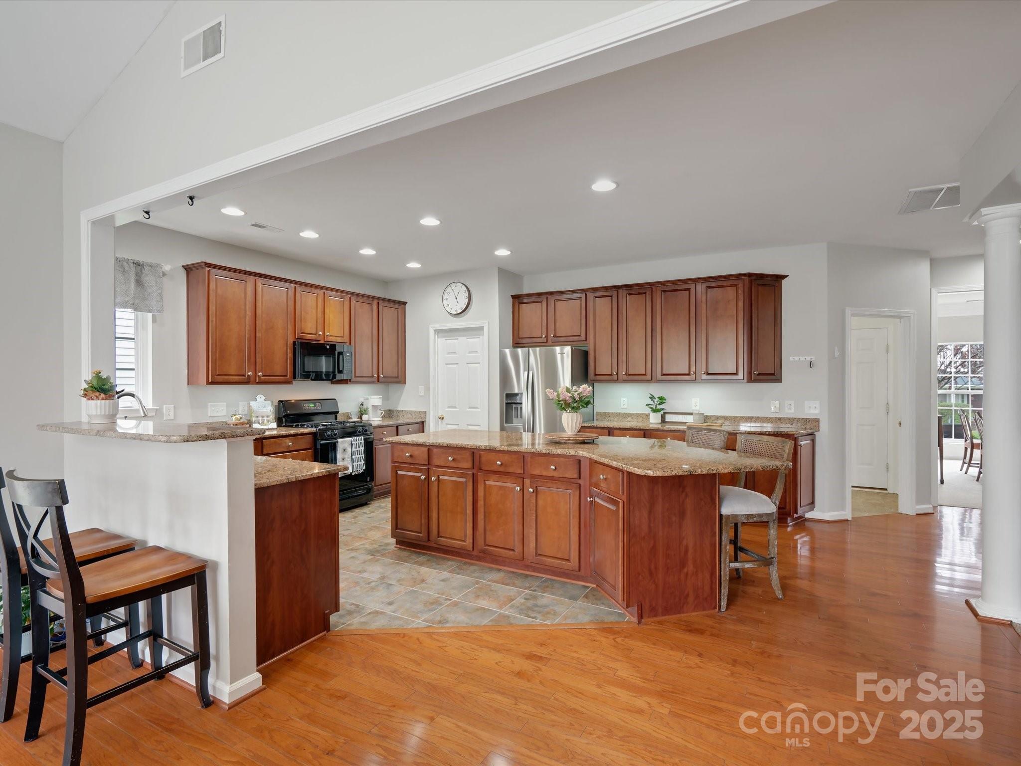 809 Circle Trace Road Monroe, NC 28110 - Photo 19 of 47 a kitchen with stainless steel appliances kitchen island granite countertop a table chairs sink and wooden cabinets