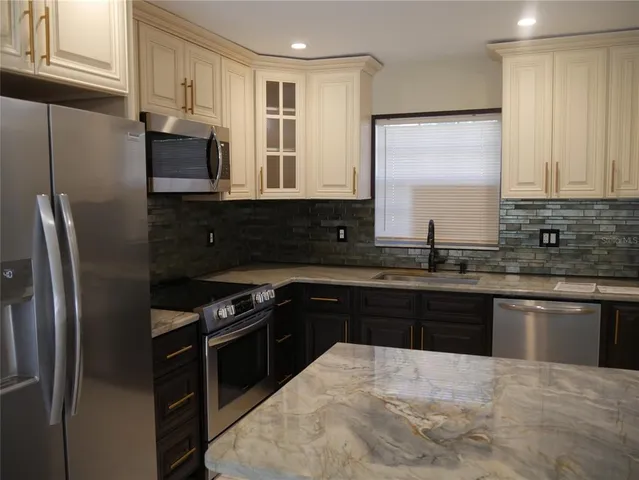 a kitchen with stainless steel appliances granite countertop a stove a sink and a refrigerator