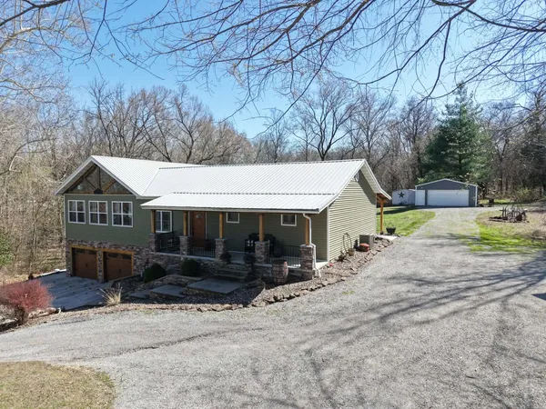 a view of a house with a yard and large tree