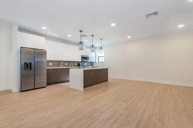 a kitchen with stainless steel appliances granite countertop a refrigerator a sink a stove and a microwave