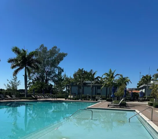 a view of swimming pool with seating space and trees in the background