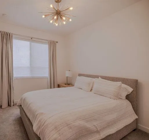 a bedroom with a large bed and a chandelier fan