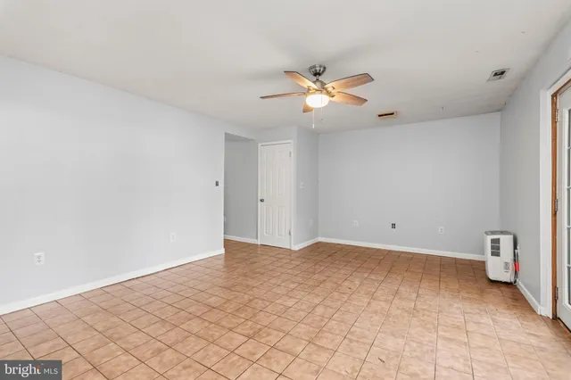 a view of an empty room and chandelier fan
