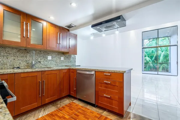 a kitchen with stainless steel appliances granite countertop wooden cabinets a refrigerator and a sink