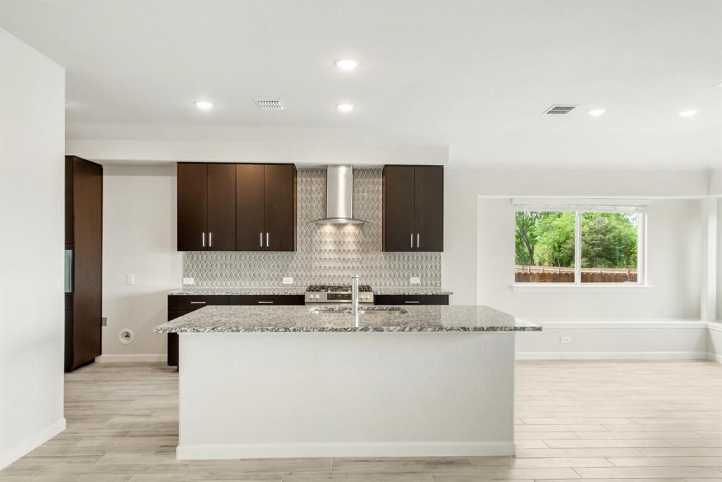 920 Elk Ridge Run Godley, TX 76044 - Photo 14 of 34 Kitchen island featuring a sink with a gooseneck faucet, dark wood-finish cabinetry, a contemporary tile backsplash, stainless steel appliances, and recessed lighting