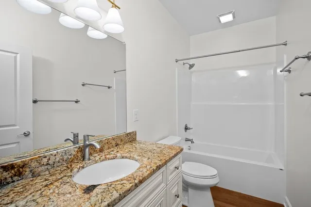 a bathroom with a granite countertop sink toilet a mirror and shower