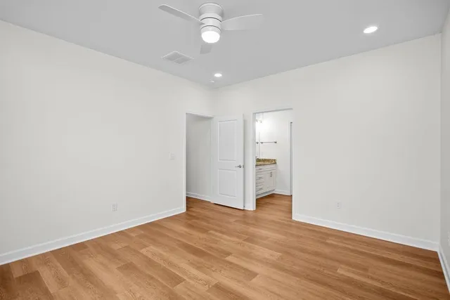 an empty room with wooden floor and ceiling fan