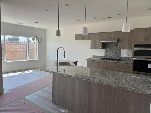 a kitchen with stainless steel appliances granite countertop a sink a stove and a wooden cabinets