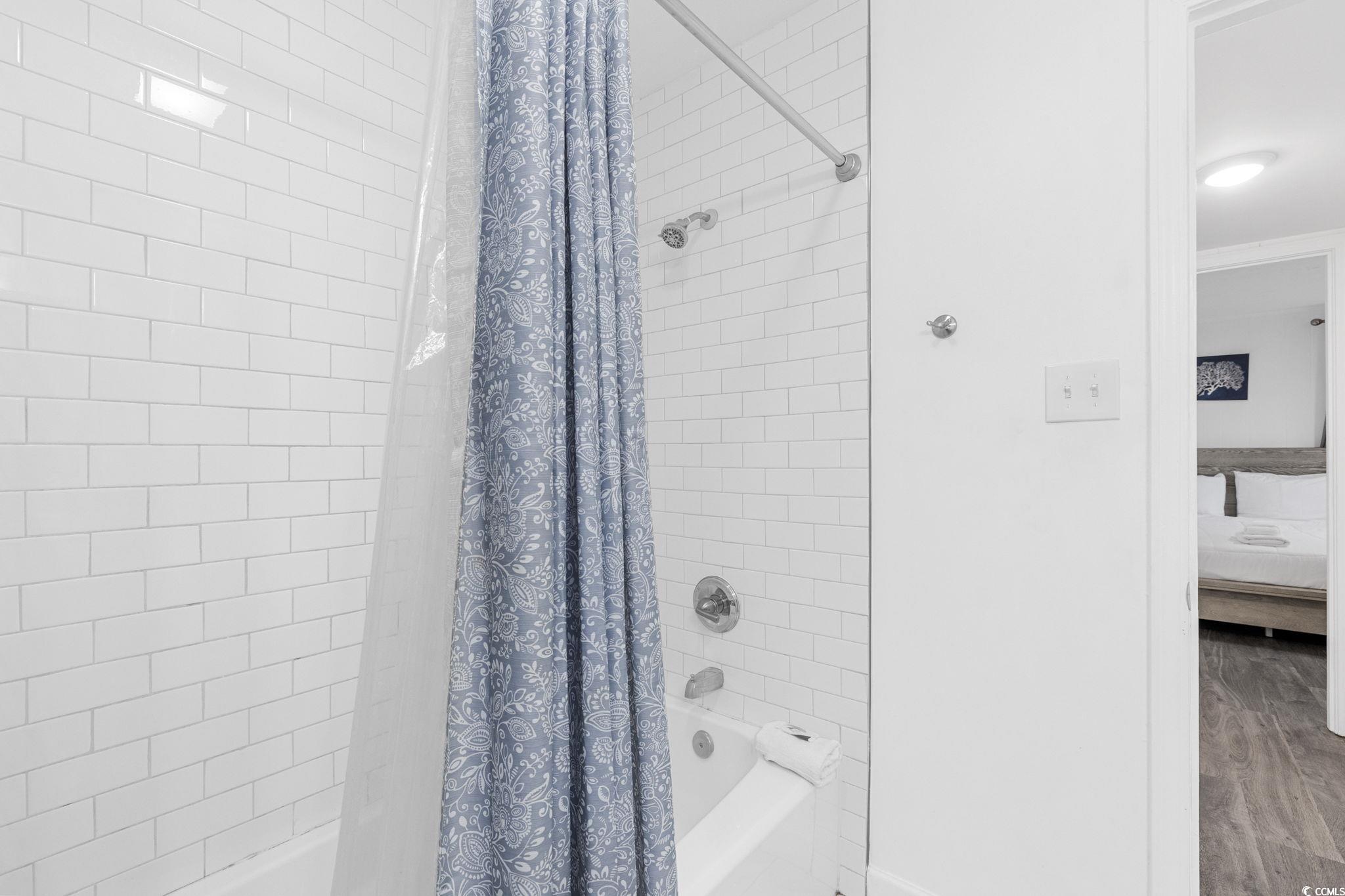 409 17th Avenue North, Unit 3 Myrtle Beach, SC 29577 - Photo 16 of 16 Full bathroom featuring shower / bath combination with curtain, connected bathroom, and wood finished floors