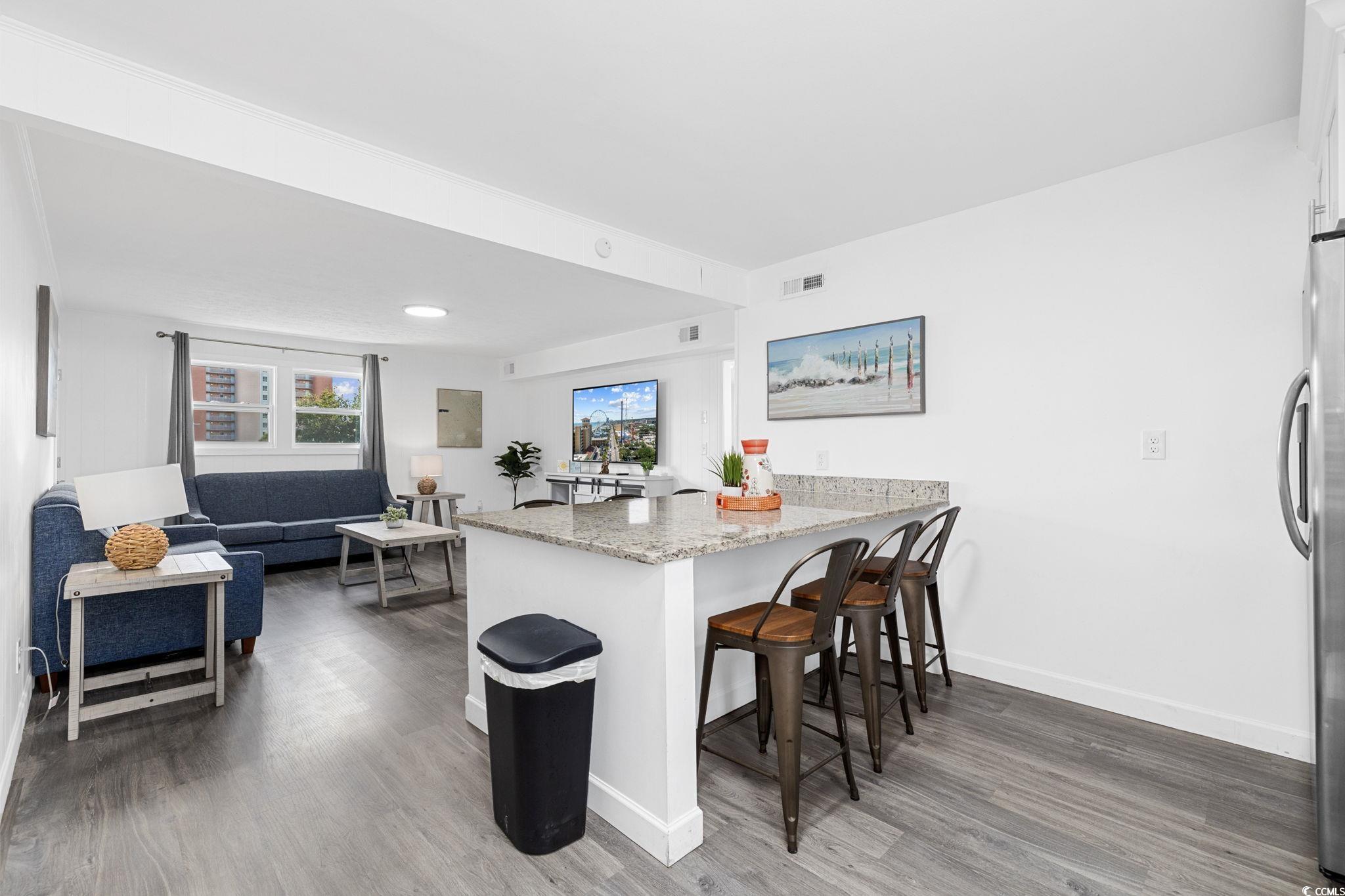 409 17th Avenue North, Unit 3 Myrtle Beach, SC 29577 - Photo 2 of 16 Kitchen featuring dark wood-type flooring, light stone countertops, a peninsula, and a breakfast bar area