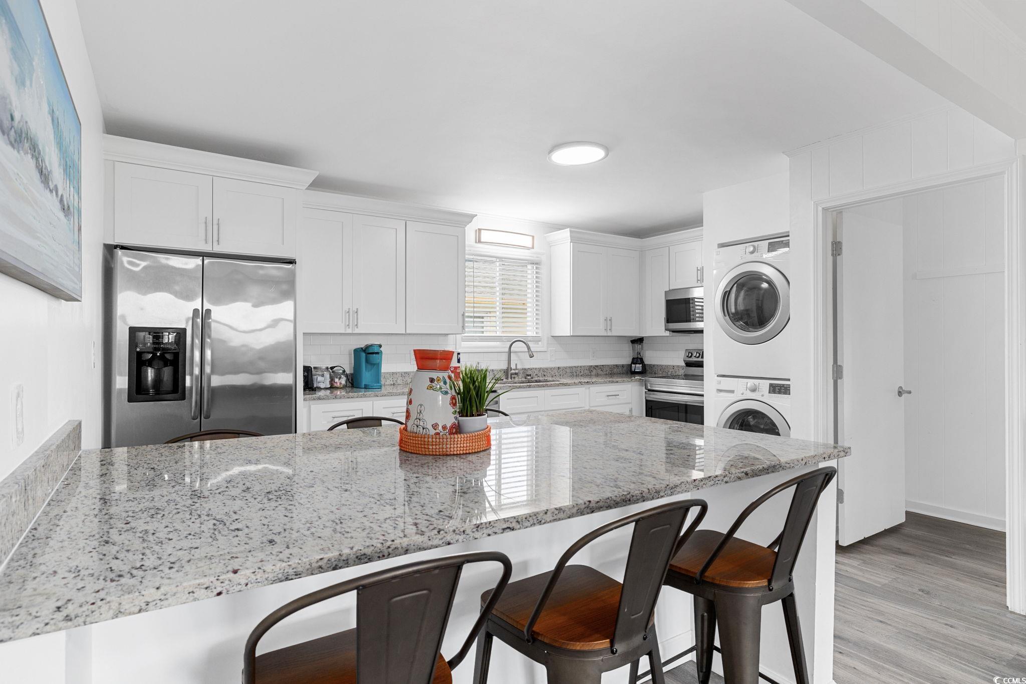 409 17th Avenue North, Unit 3 Myrtle Beach, SC 29577 - Photo 7 of 16 Kitchen featuring a breakfast bar area, appliances with stainless steel finishes, light stone countertops, and backsplash