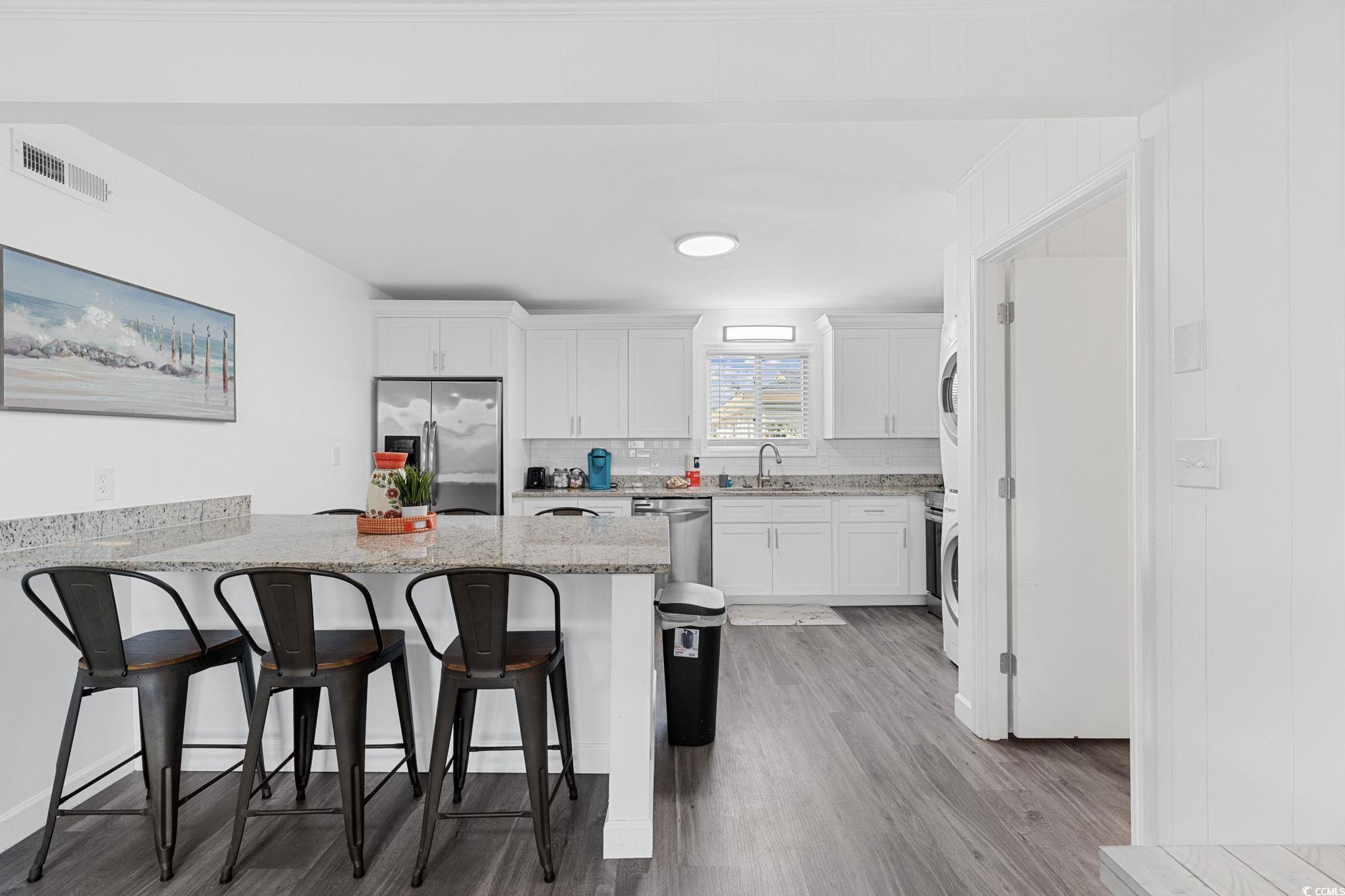 409 17th Avenue North, Unit 3 Myrtle Beach, SC 29577 - Photo 8 of 16 Kitchen featuring white cabinetry, a kitchen bar, stainless steel appliances, backsplash, and a peninsula