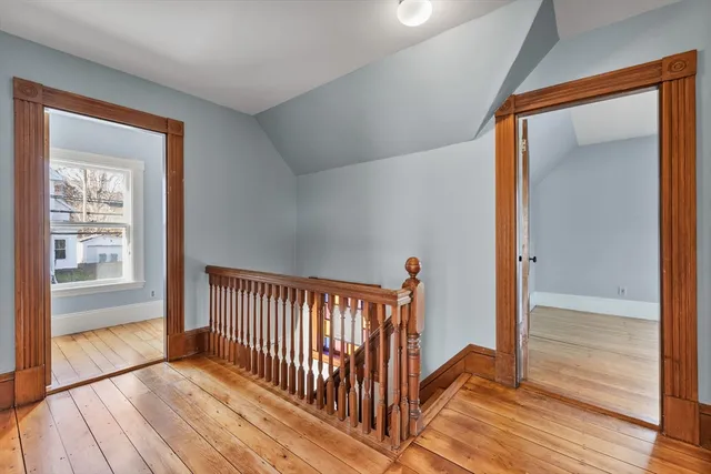 a view of a hallway with wooden floor and a bathroom