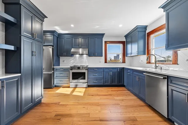 a large kitchen with stainless steel appliances granite countertop a stove refrigerator and cabinets