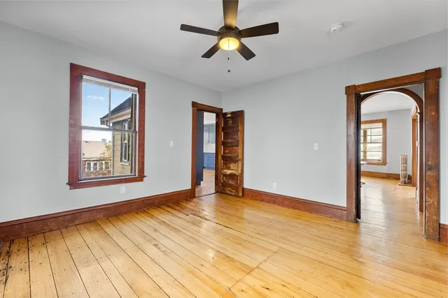 a view of an empty room with window and wooden floor