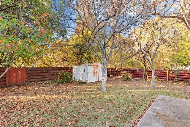 a backyard of a house with barbeque oven and large tree