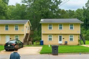 a front view of a house with a garden and trees