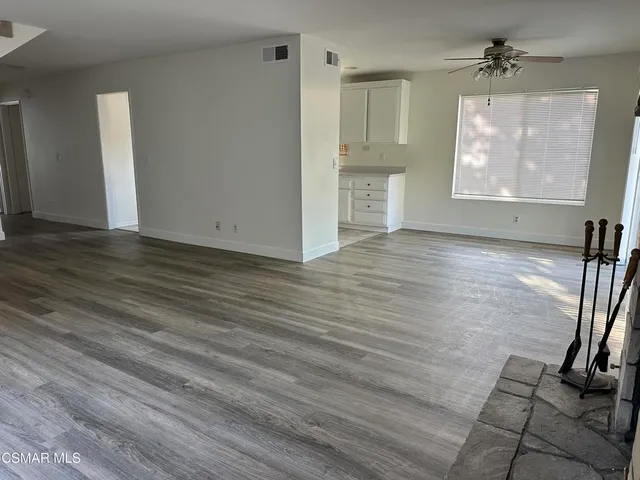 an empty room with wooden floor fireplace and windows