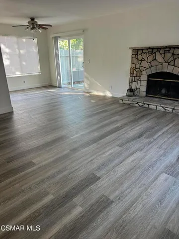 an empty room with wooden floor fireplace and windows