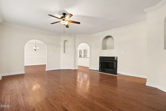 a view of an empty room with a fireplace and wooden floor