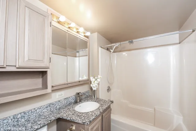 a bathroom with a granite countertop sink mirror and a bathtub