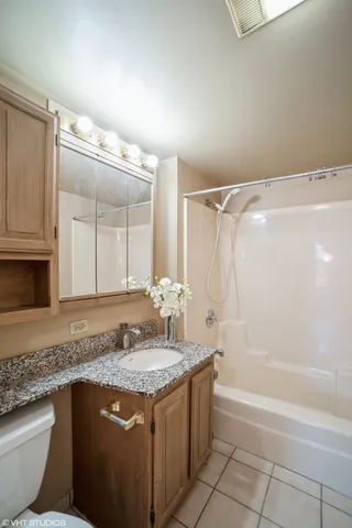 a bathroom with a granite countertop sink a toilet and bathtub