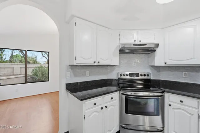 a kitchen with stainless steel appliances granite countertop white cabinets and a stove