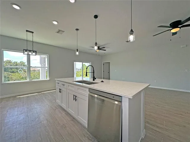 a kitchen with a sink a center island a wooden floor and a window