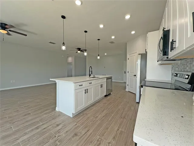 a large white kitchen with a stove a sink dishwasher and a refrigerator with wooden floor