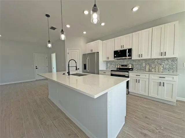 a kitchen with kitchen island a sink stainless steel appliances and cabinets