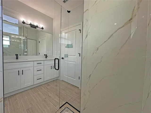 a spacious bathroom with a shower a sink a mirror and a shower