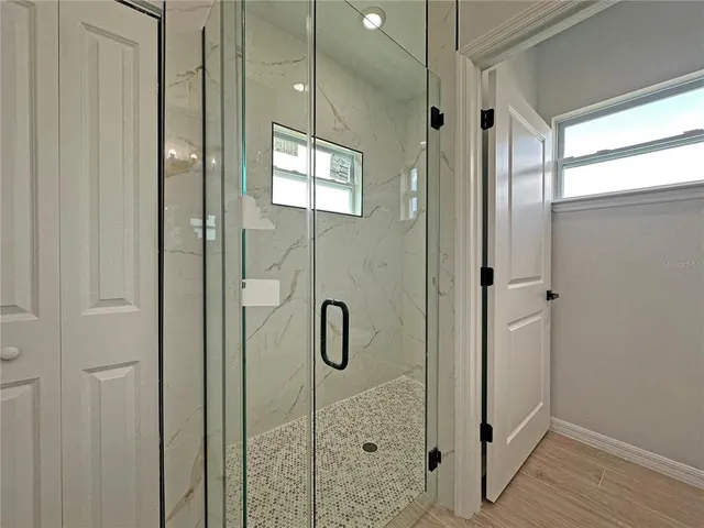 a bathroom with a glass shower door and a window