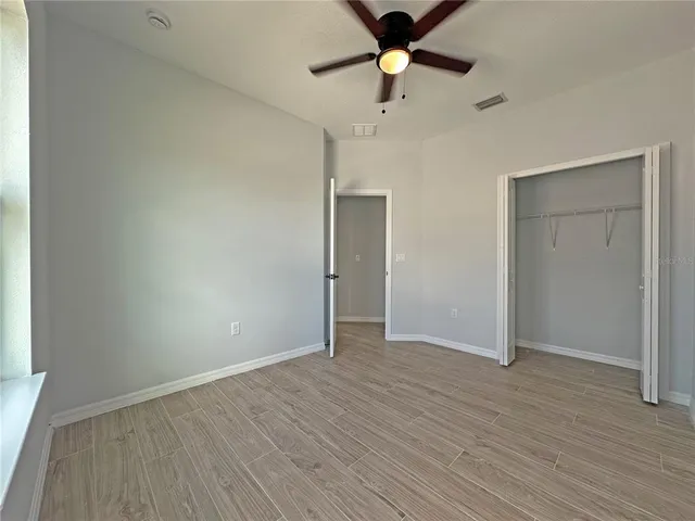 an empty room with wooden floor and a ceiling fan