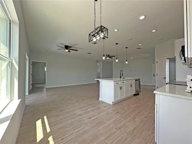 a view of a kitchen with kitchen island a sink wooden floor and a large window