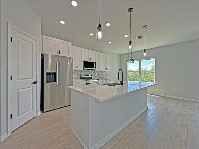 a large kitchen with kitchen island a refrigerator a stove a sink and a chandelier