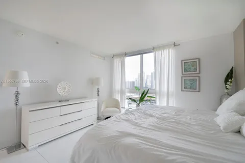 a bedroom with a bed and large windows