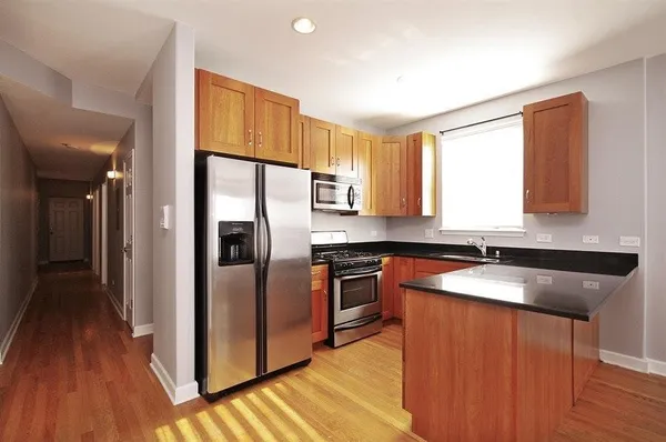 a kitchen with granite countertop stainless steel appliances a counter top space and a refrigerator
