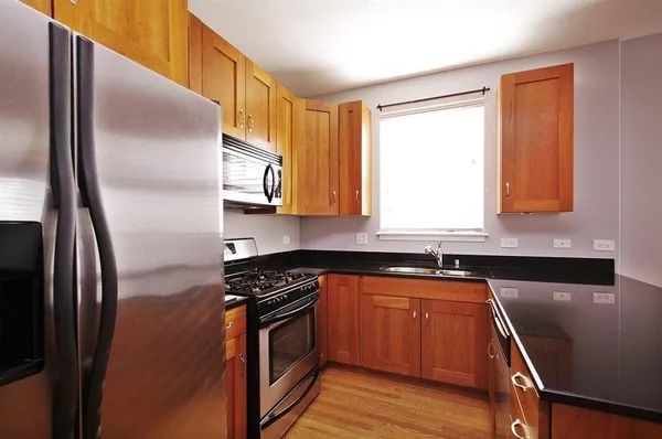 a kitchen with stainless steel appliances granite countertop a refrigerator a sink dishwasher a stove and white countertops with wooden floor