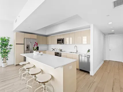 a large white kitchen with stainless steel appliances a stove a table and chairs